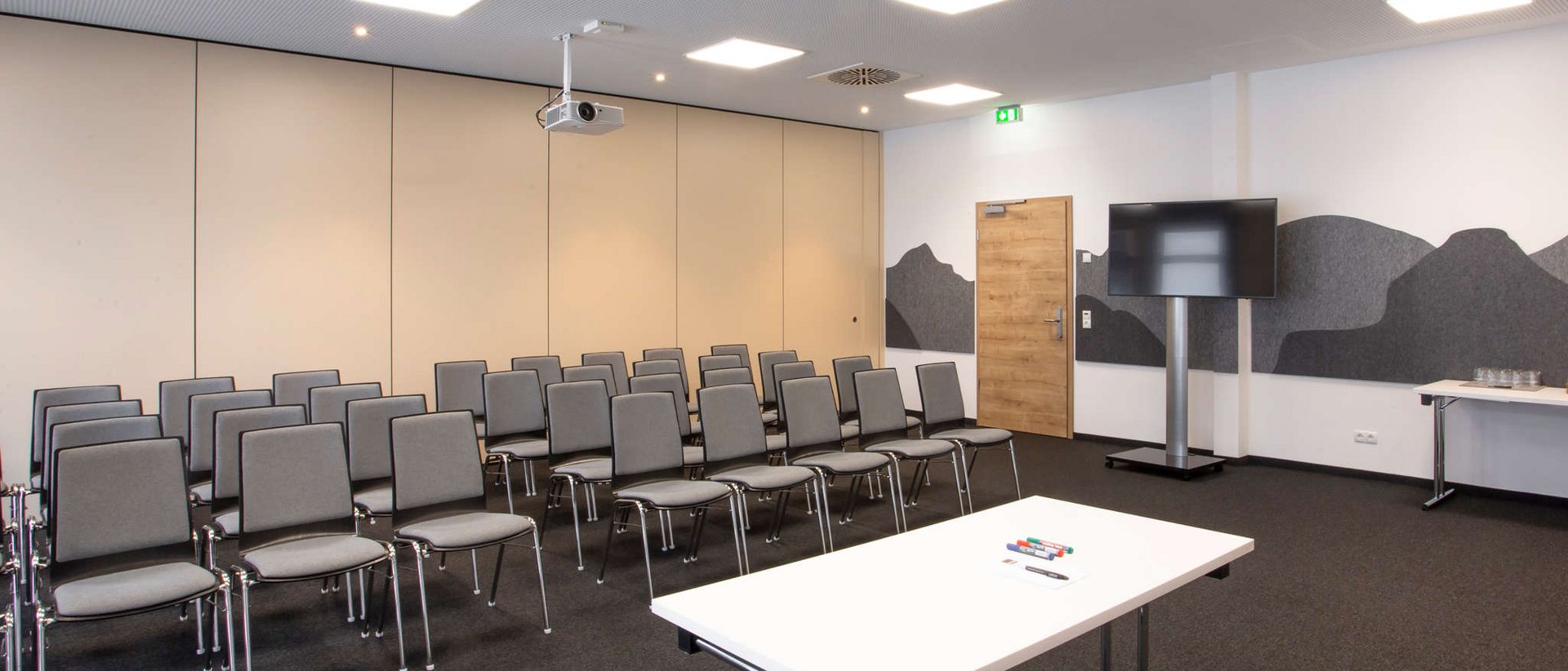 7557 Moderner Konferenzraum mit Stuhlreihen, Tisch und Bildschirm
