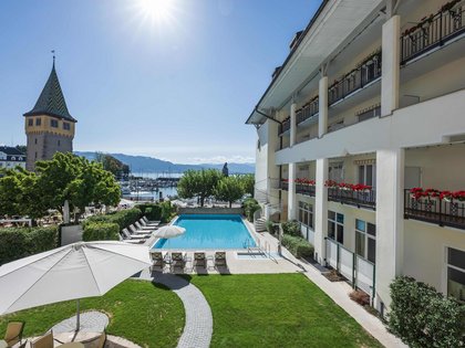 Lerch Businesswelten - Inspirationen an einem Tag Hotelgarten mit Pool, Liegen und Blick auf See, Berge und historischen Turm