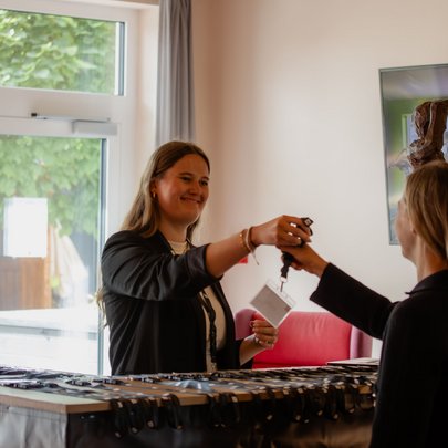 Lerch Businesswelten - Inspirationen an einem Tag Zwei Frauen übergeben sich an einem Tisch einen Schlüssel