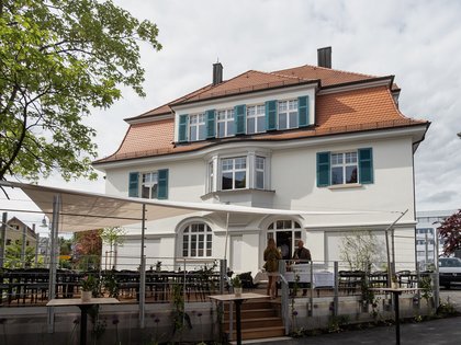 Lerch Businesswelten - Inspirationen an einem Tag Großes weißes Haus mit rotem Dach und Außenterrasse mit Tischen und Stühlen
