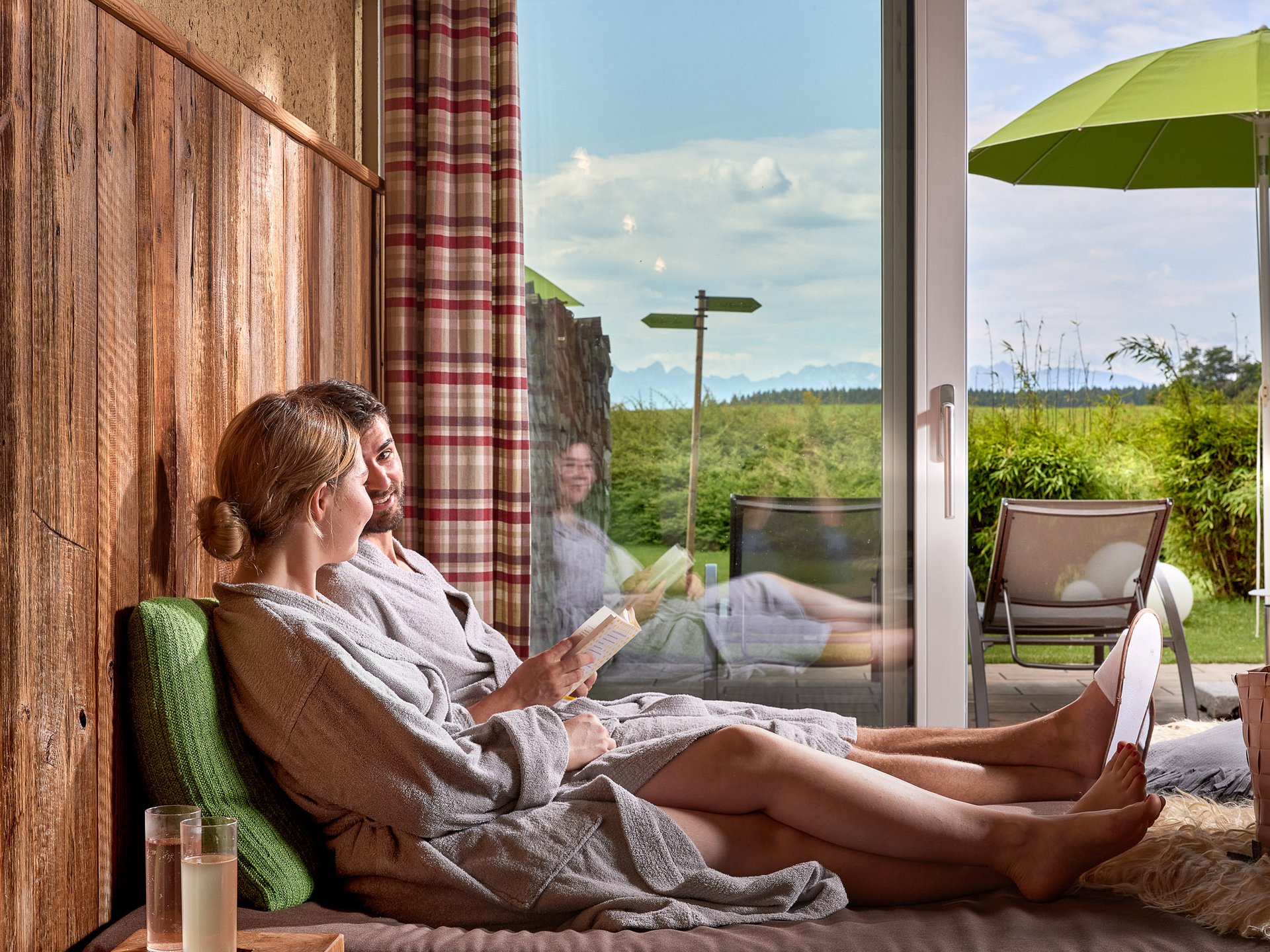 Paar in Bademänteln entspannt sich drinnen mit Blick auf Terrasse und Garten