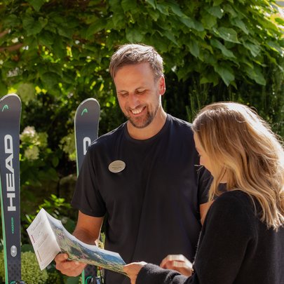 Lerch Businesswelten - Inspirationen an einem Tag Mann und Frau betrachten gemeinsam eine Karte neben zwei Skiern im Garten