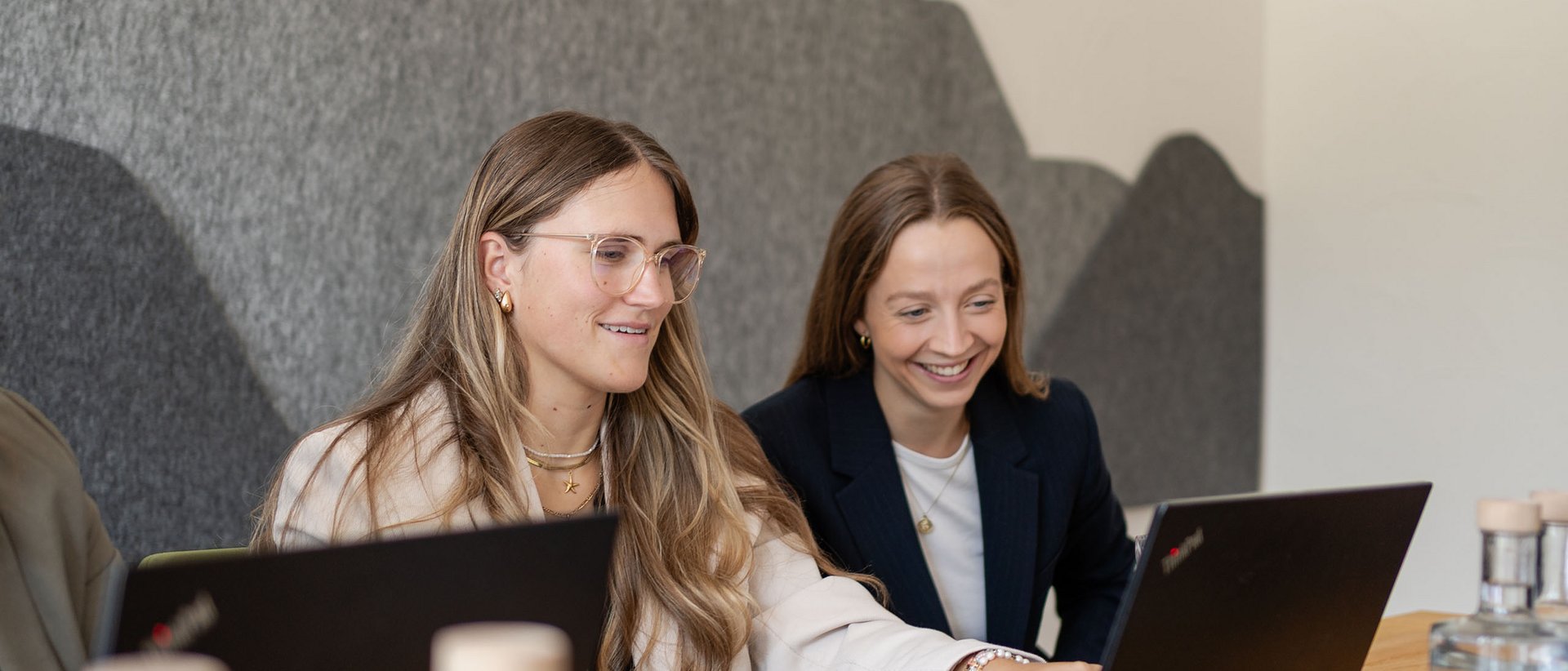 7557 Zwei Frauen arbeiten gemeinsam an einem Laptop in einem modernen Büro