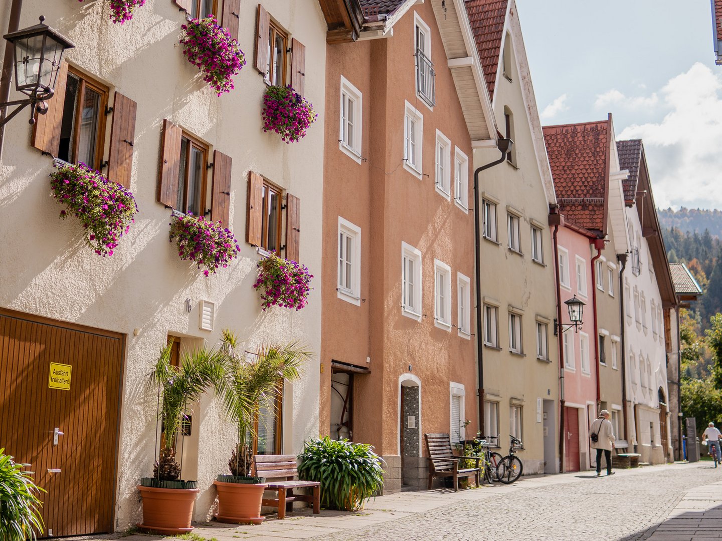 Autofrei in Das Weitblick Allgäu reisen Straße mit bunten Häusern, Blumen und Bänken in einer sonnigen Kleinstadt