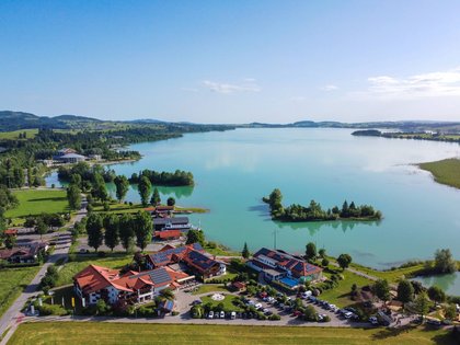 Lerch Businesswelten - Inspirationen an einem Tag Luftaufnahme eines Sees mit Inseln und Gebäuden am Ufer bei klarem Himmel