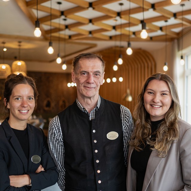Lerch Businesswelten - Inspirationen an einem Tag Drei lächelnde Hotelmitarbeiter in einem modernen Restaurant
