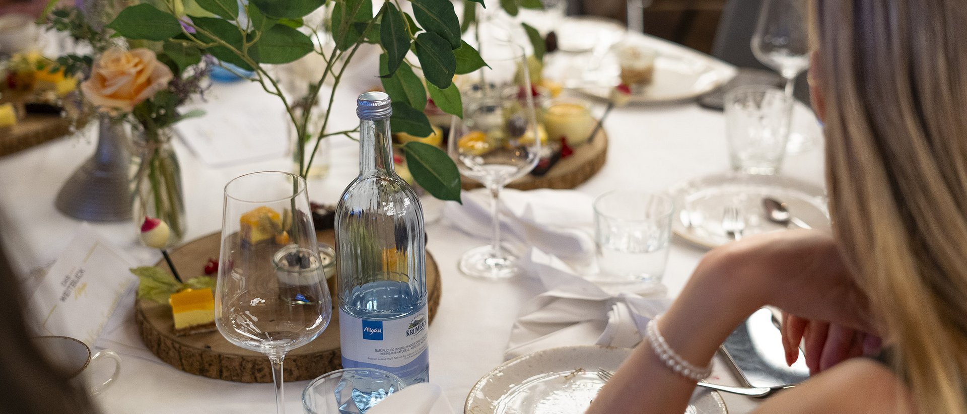Die wichtigsten Informationen im Überblick Eleganter gedeckter Tisch mit Wasserflasche, Gläsern und Blumenarrangement