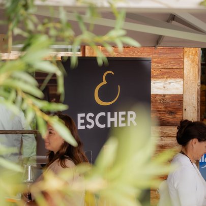 Lerch Businesswelten - Inspirationen an einem Tag Schild mit dem Namen Escher an einem Holzgebäude, teilweise von Pflanzen verdeckt