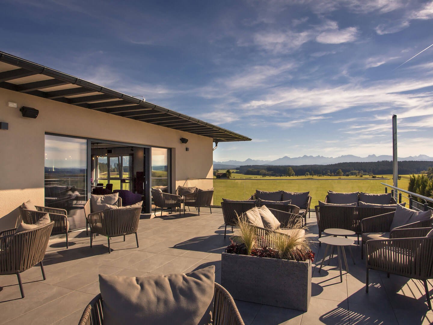 6324 Terrasse mit modernen Sitzmöbeln und Blick auf grüne Wiesen und Berge