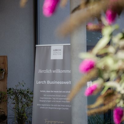 Lerch Businesswelten - Inspirationen an einem Tag Willkommensbanner der Lerch Businesswelt neben blühenden Pflanzen