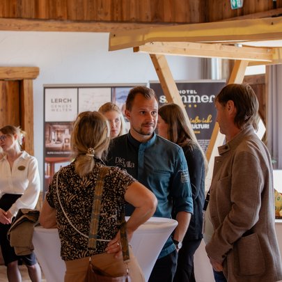 Lerch Businesswelten - Inspirationen an einem Tag Mehrere Menschen unterhalten sich bei einer Veranstaltung in einem rustikalen Raum