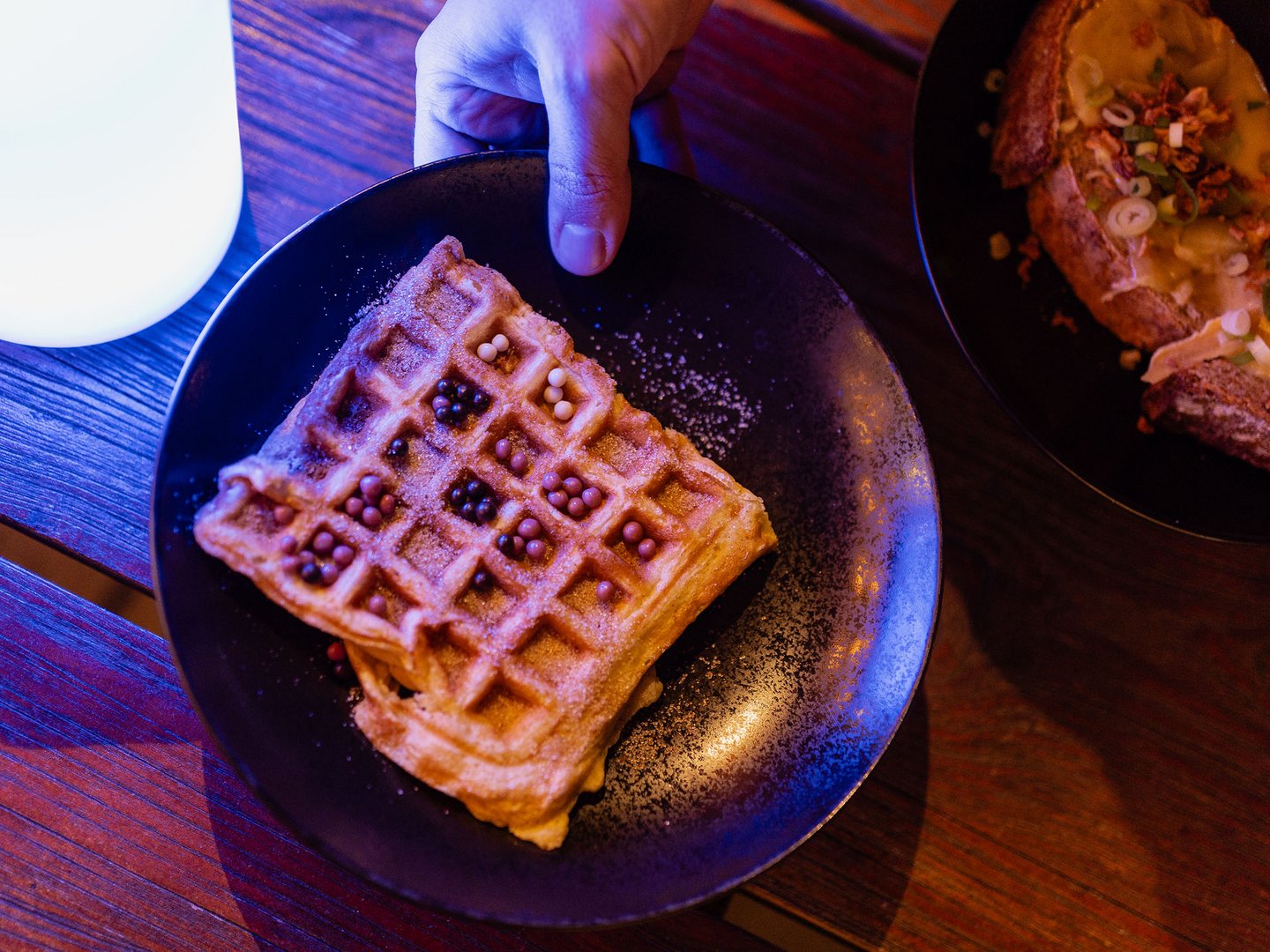 Lichterzauber im Weitblick Allgäu Belgische Waffel mit Beeren und Puderzucker auf einem schwarzen Teller