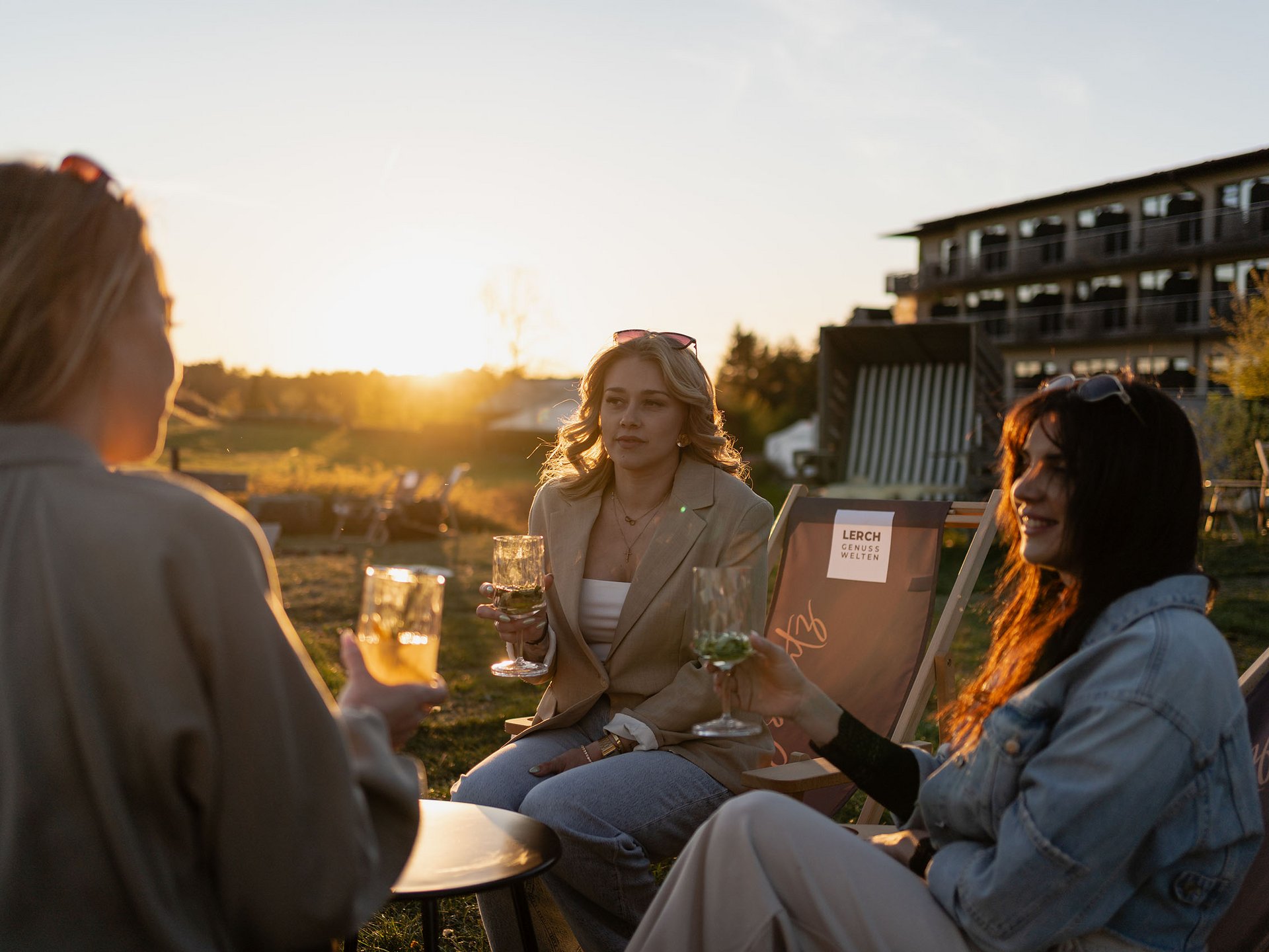 Teambildung & Gruppenevents im Allgäu Drei Frauen sitzen draußen und trinken bei Sonnenuntergang