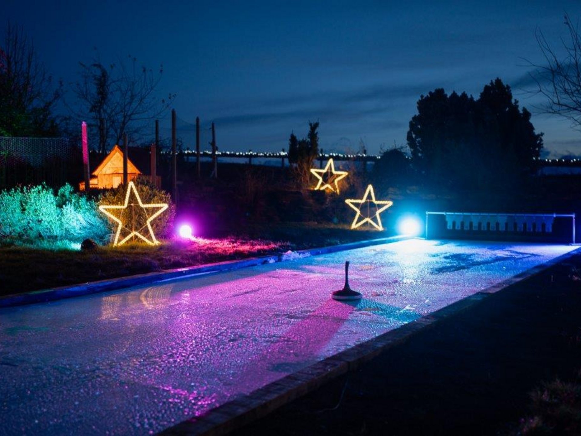 Teambildung & Gruppenevents im Allgäu Beleuchtete Eisstockbahn mit Stern-Dekorationen bei Nacht