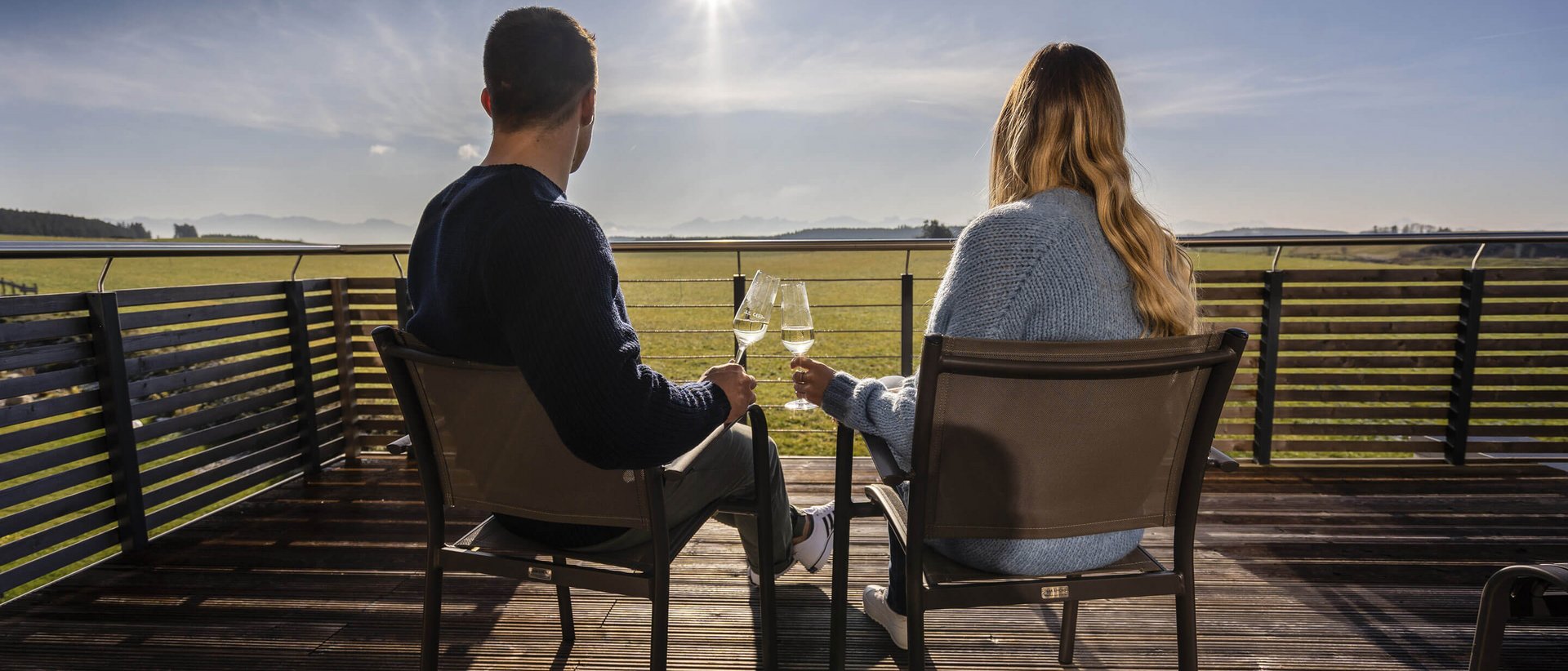 Hotel Das Weitblick Allgäu | Wellnesshotel Marktoberdorf Paar sitzt auf Terrasse und genießt Sonnenuntergang mit Weingläsern