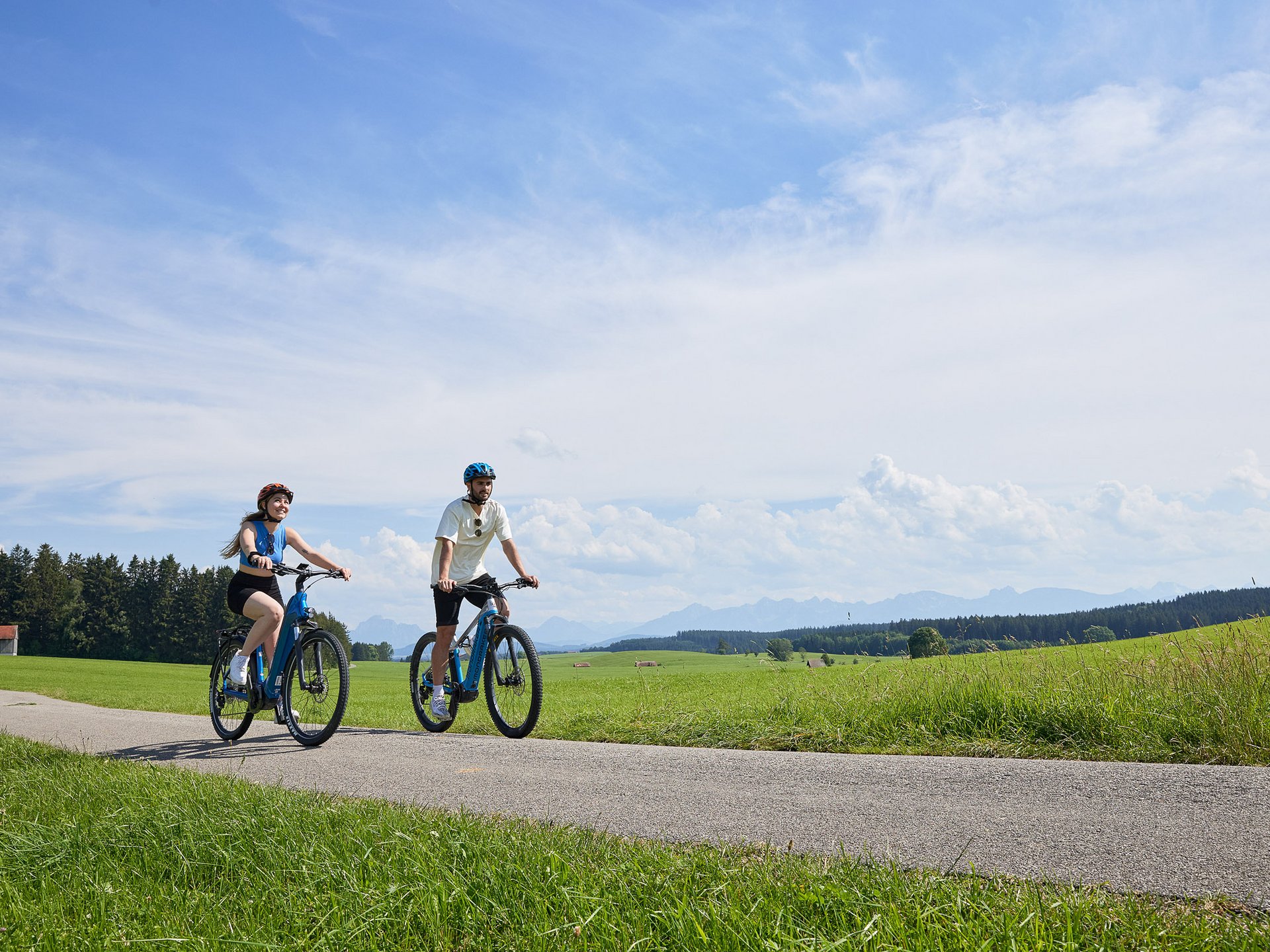 Teambildung & Gruppenevents im Allgäu Zwei Personen fahren mit Fahrrädern auf einem Weg durch grüne Wiesen
