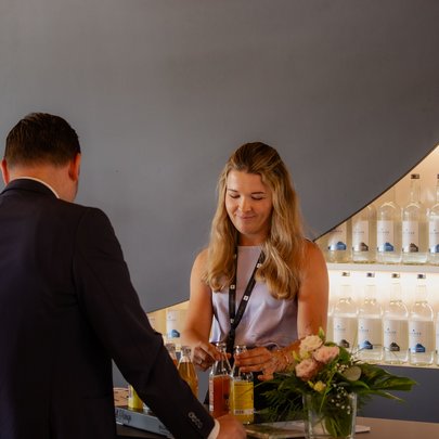 Lerch Businesswelten - Inspirationen an einem Tag Mitarbeiterin schenkt an einer Bar Getränke für einen Gast ein