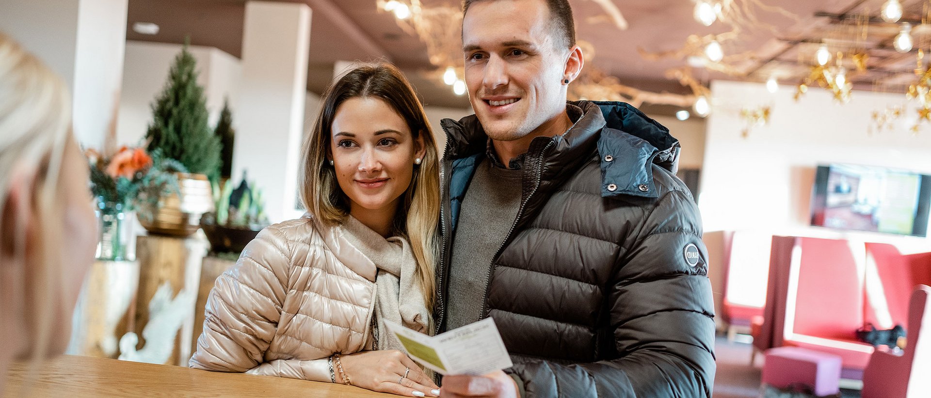 Autofrei in Das Weitblick Allgäu reisen Junges Paar checkt an der Hotelrezeption ein