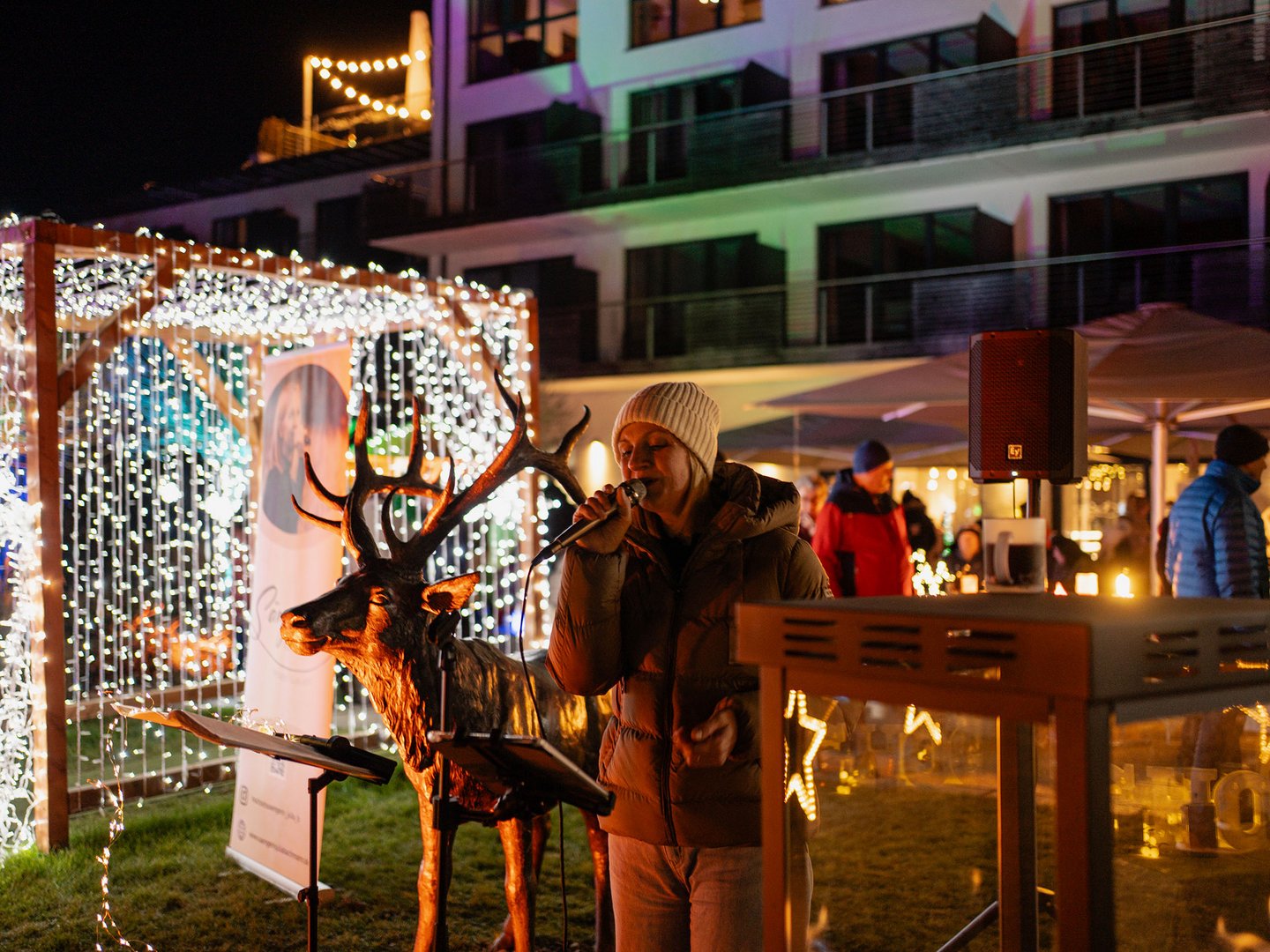 Lichterzauber im Weitblick Allgäu Sänger mit Mikrofon neben beleuchtetem Rentier auf einem Wintermarkt