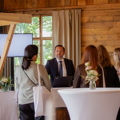 Lerch Businesswelten - Inspirationen an einem Tag Empfang mit Gästen und einem Mann am Laptop in einer holzverkleideten Lobby