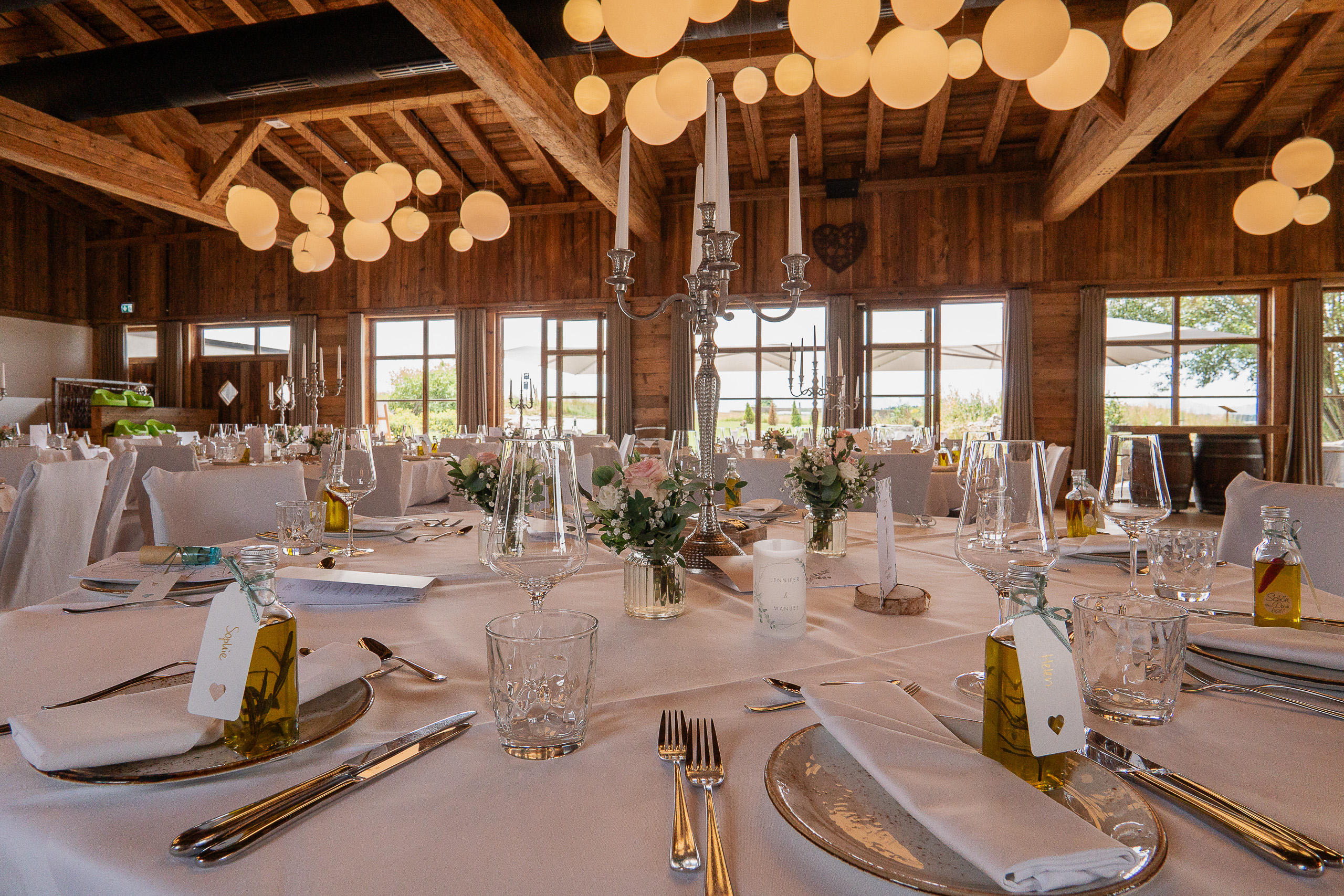 Feststadl Allgäu mit Holzdecken, runder Tischdekoration und Bergblick. Feststadl Allgäu Hochzeitssaal